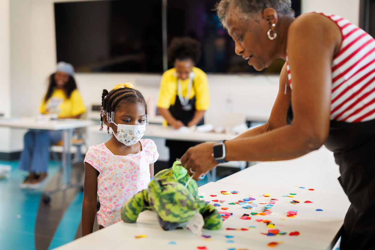 Pailyn Williams, 5, of Crystal Springs watches as volunteer Cora Jones places a heart into her stuffed bear.
